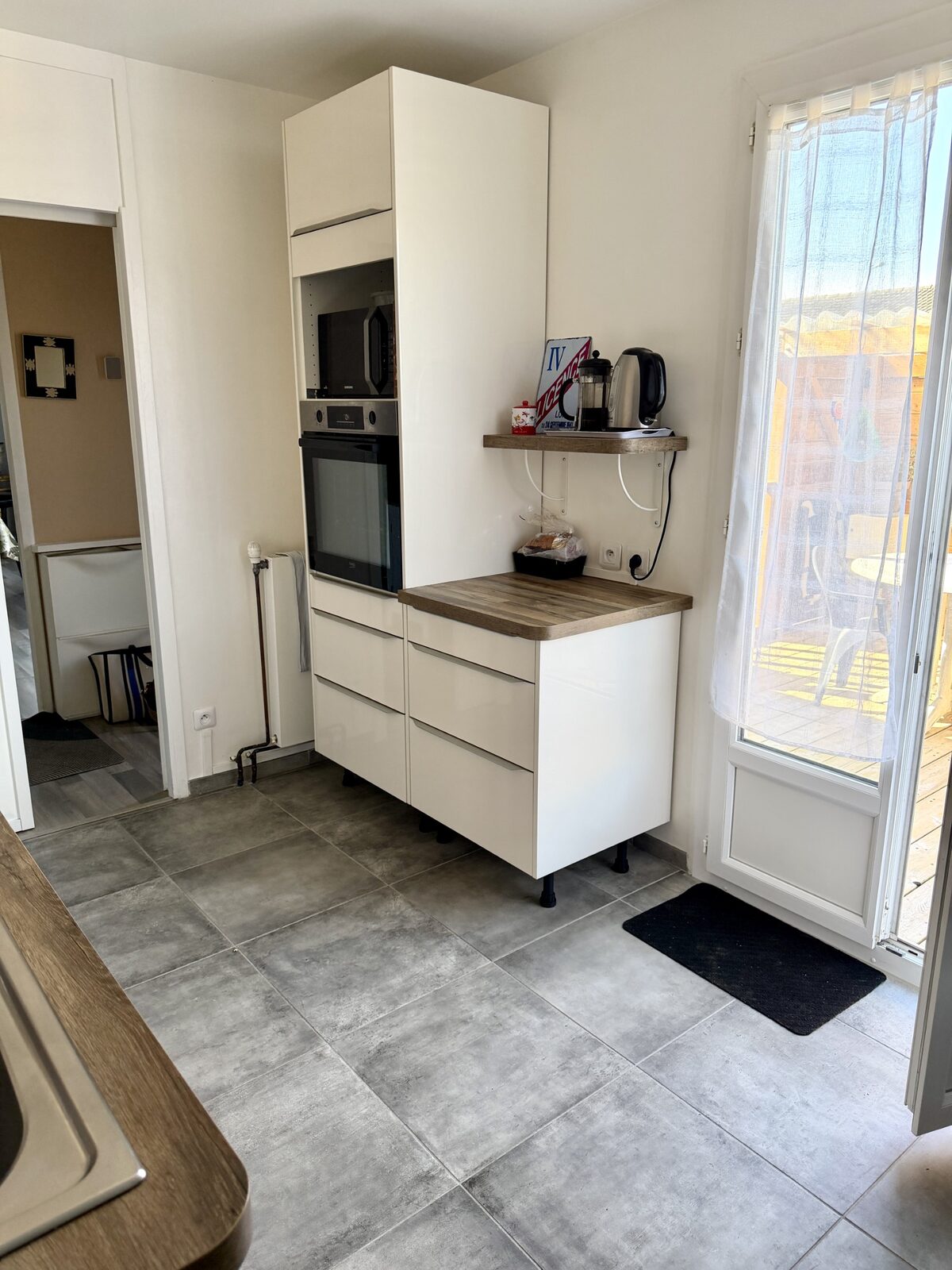 Cuisine avec four, micro-ondes et porte-fenêtre sur la terrasse, maison à Pessac